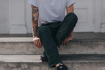 Man with tattooed arm sitting on concrete steps