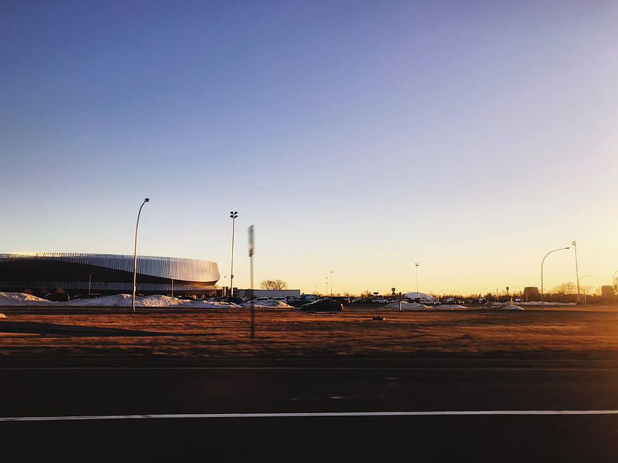 Modern stadium architecture at sunset with snow and road