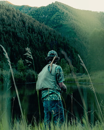 Man fly fishing in mountain lake at sunset