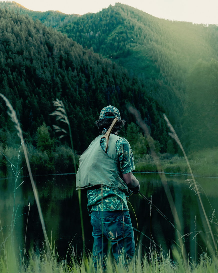 Man fly fishing in mountain lake at sunset