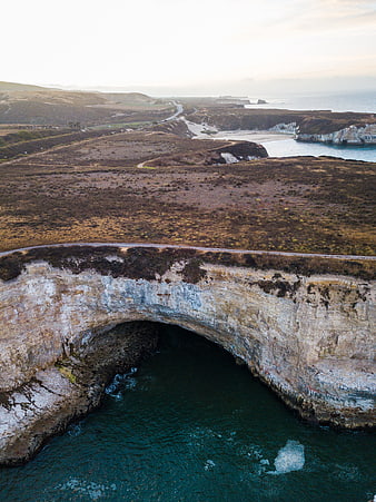 Aerial View of Natural Rock Arch Bridge Over Ocean