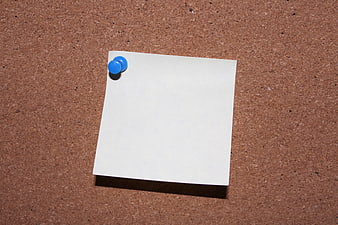 Blank white paper pinned to cork board with blue thumbtack