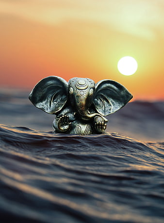 Ganesha statue on ocean waves at sunset