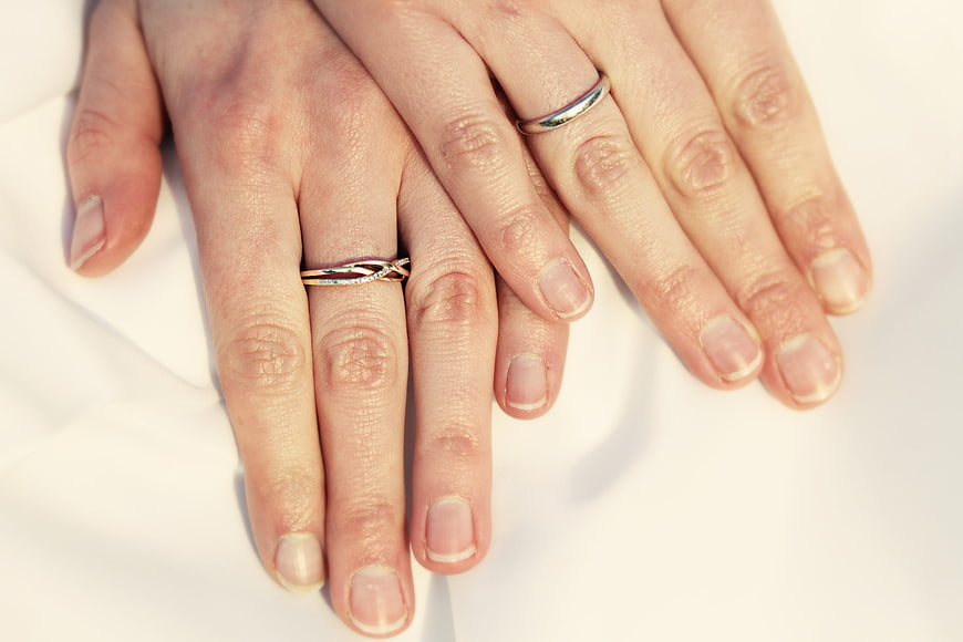 Close-up of two hands with wedding rings on white fabric