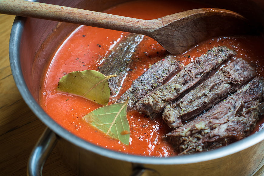Sliced beef stew in tomato sauce with bay leaves