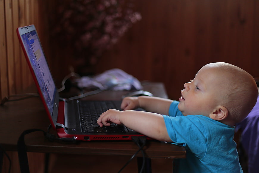 Baby boy typing on laptop computer screen