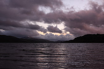 Dramatic moody lake landscape with storm clouds and mountains