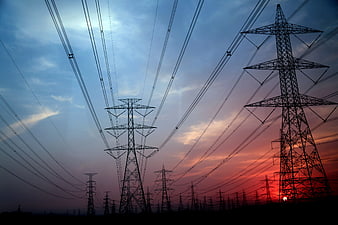Silhouetted High Voltage Transmission Towers Against Dramatic Sunset Sky