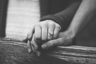 Black and white photo of couple holding hands with engagement ring