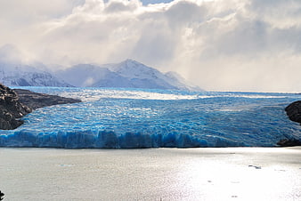 Majestic Blue Glacier with Snow-Capped Mountains and Sunlit Water