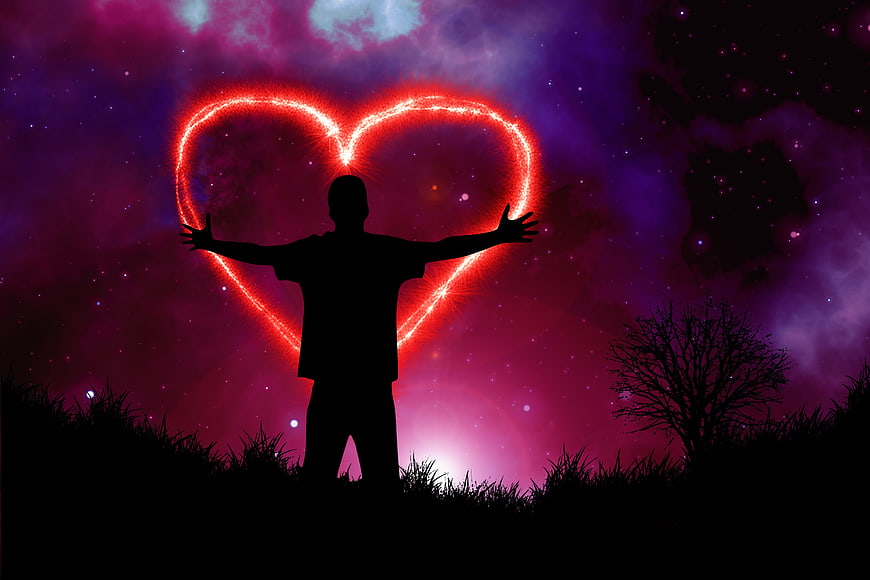 Silhouette of man with glowing heart in cosmic sky