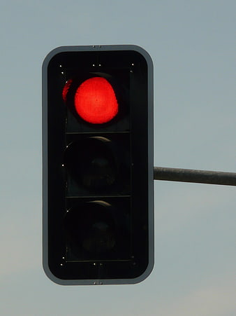 Red traffic light signal against a clear blue sky