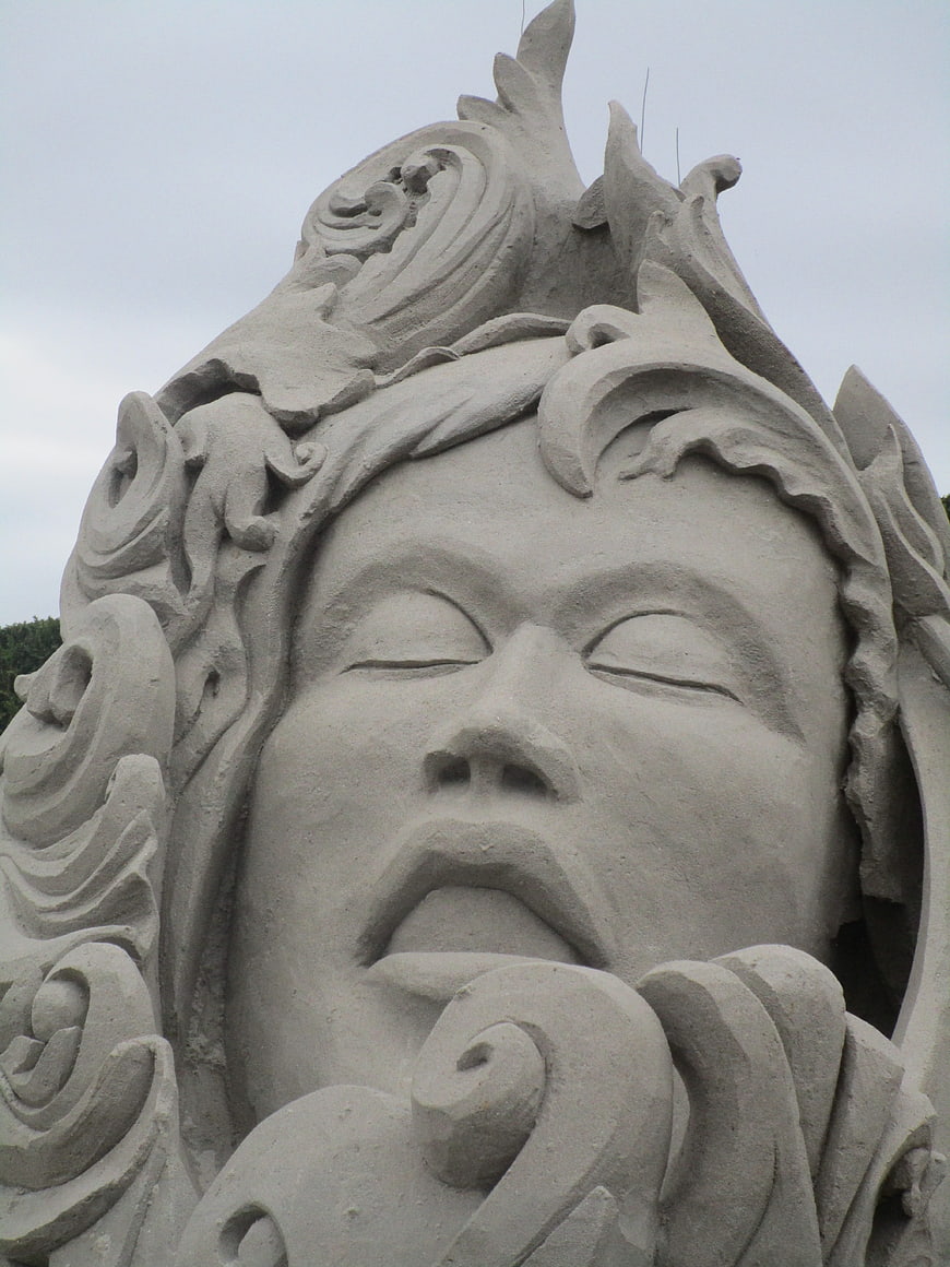 Close-up of intricate sand sculpture face with closed eyes