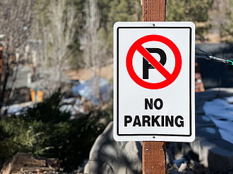No Parking Sign on Wooden Post with Blurred Background