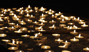 Rows of lit tea light candles in a dark church setting