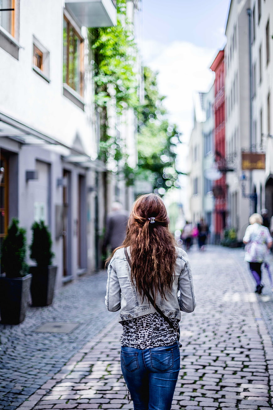 Woman Walking Away on Cobblestone Street