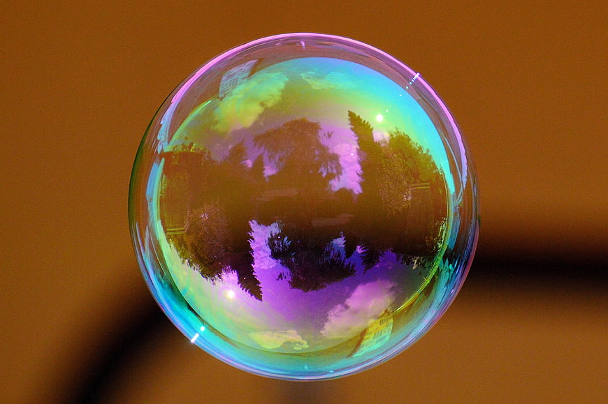 Iridescent soap bubble reflecting trees and sky