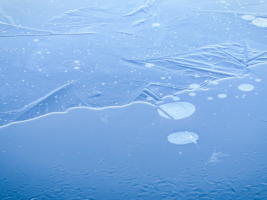 Close-up of frozen ice surface with trapped air bubbles and cracks