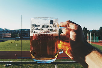 Hand holding beer mug at sports stadium