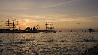 Silhouetted Tall Ships and Ferris Wheel at Sunset Harbor