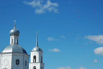 White Orthodox Church with Balloons in Blue Sky