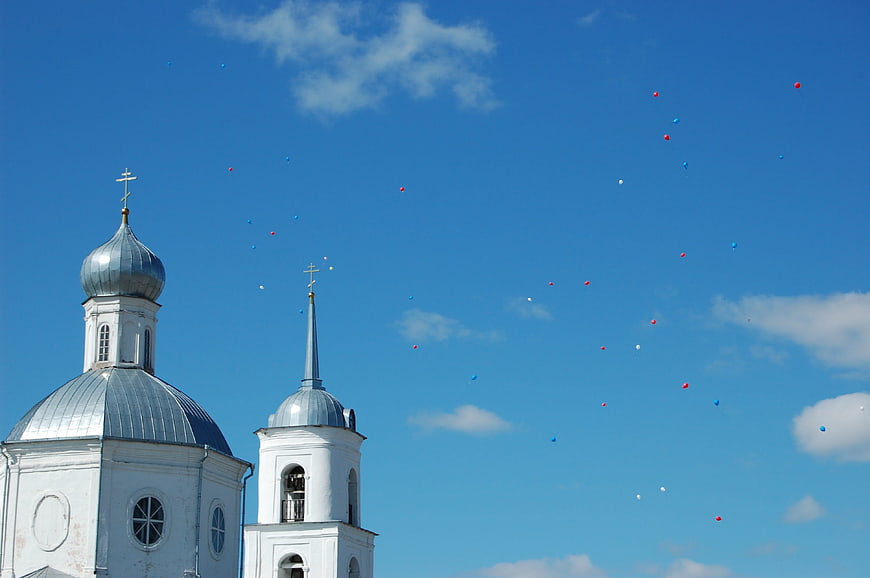 White Orthodox Church with Balloons in Blue Sky