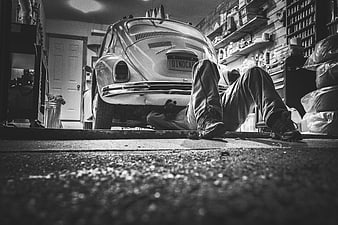 Mechanic working under vintage car in garage