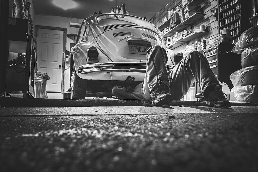 Mechanic working under vintage car in garage