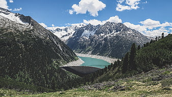 Alpine dam with turquoise reservoir and snow-capped mountains
