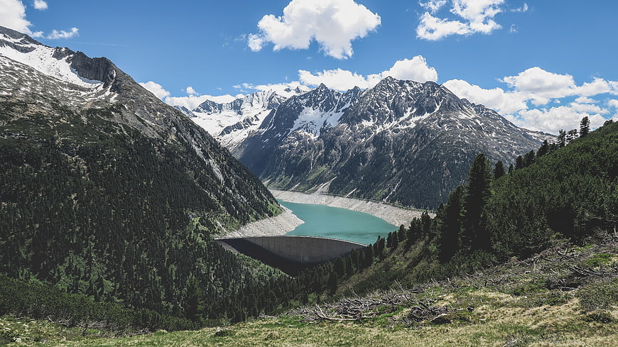 Alpine dam with turquoise reservoir and snow-capped mountains