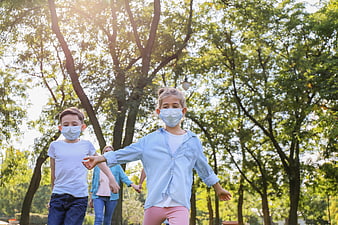 Children wearing face masks running in a sunny park