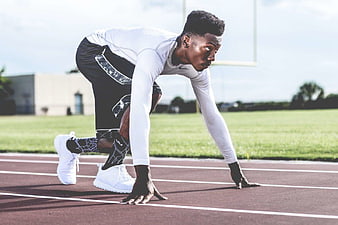 Focused Male Sprinter in Starting Position on Track