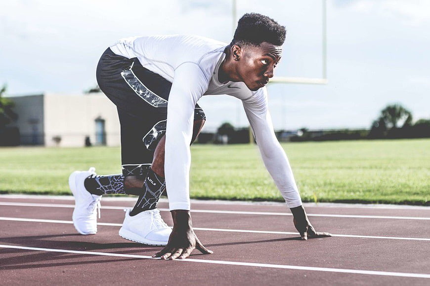 Focused Male Sprinter in Starting Position on Track