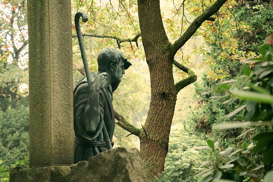 Bronze statue of pilgrim with staff in forest setting