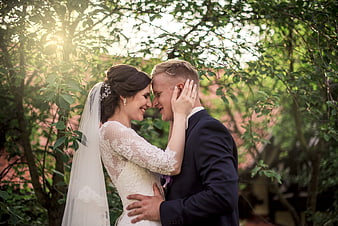 Romantic Wedding Couple Embracing Under Sunlit Green Trees