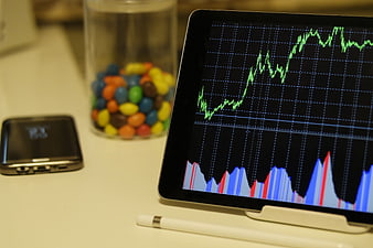 Tablet displaying stock market graph with smartphone and candy jar