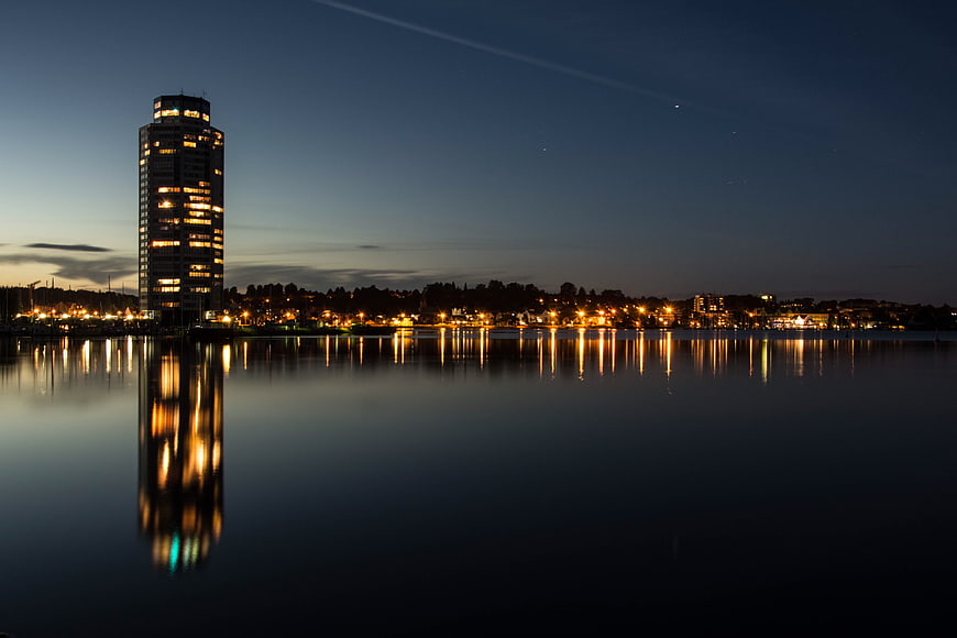City skyline at dusk with tall building reflection in calm water