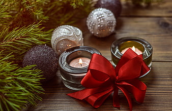 Christmas candles, pine branches, and red bow on wooden background