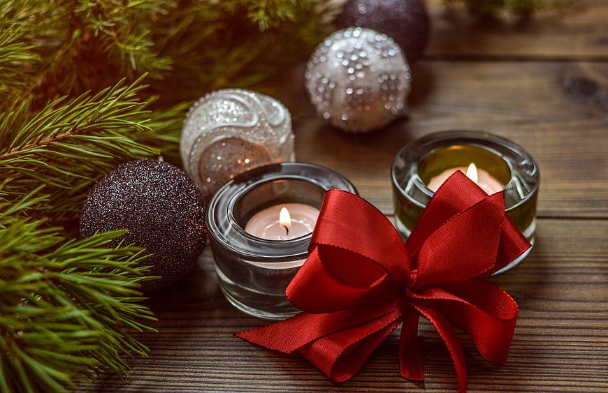 Christmas candles, pine branches, and red bow on wooden background