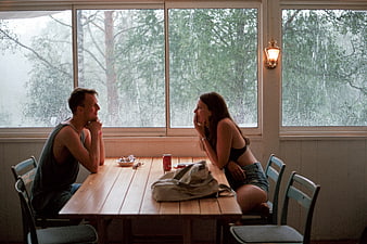 Intimate couple having lunch at a wooden table by a rainy window