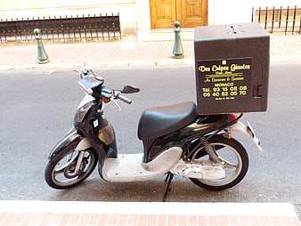 Black scooter with delivery box parked on street