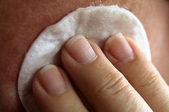 Close-up of hand using cotton pad for skincare routine