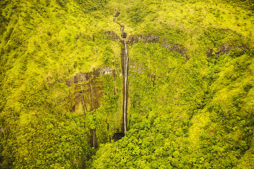 Aerial view of lush green waterfall cascading down a tropical mountain