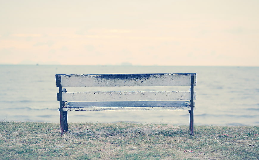 Lonely weathered wooden bench by the sea