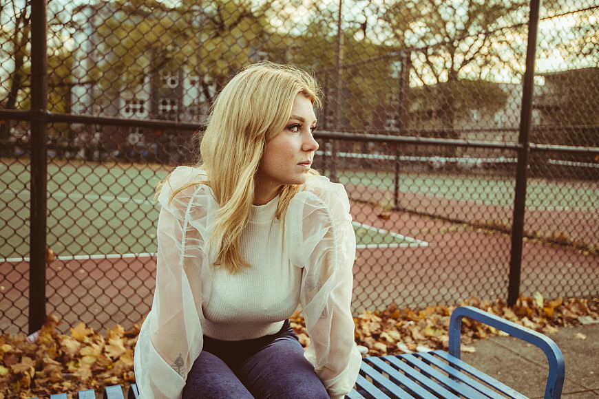 Blonde woman sitting on bench in autumn park
