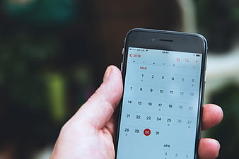 Hand holding smartphone with calendar app open