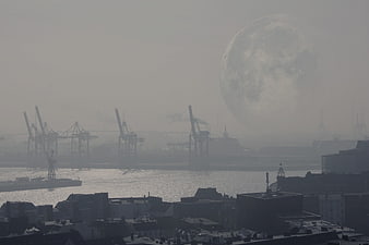 Hazy moonrise over industrial port city skyline