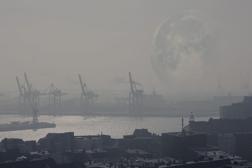 Hazy moonrise over industrial port city skyline