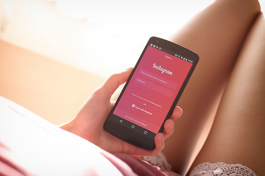Woman holding smartphone with Instagram login screen