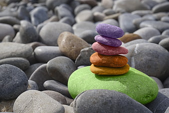 Stacked colorful stones on a pebble beach background